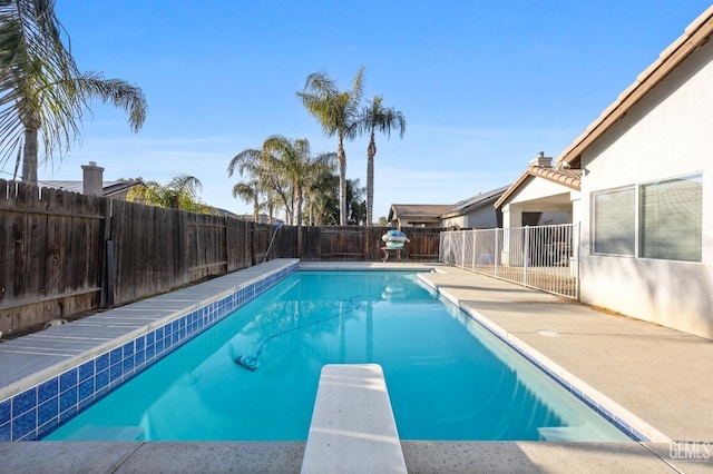 view of pool featuring a fenced in pool, a fenced backyard, and a diving board