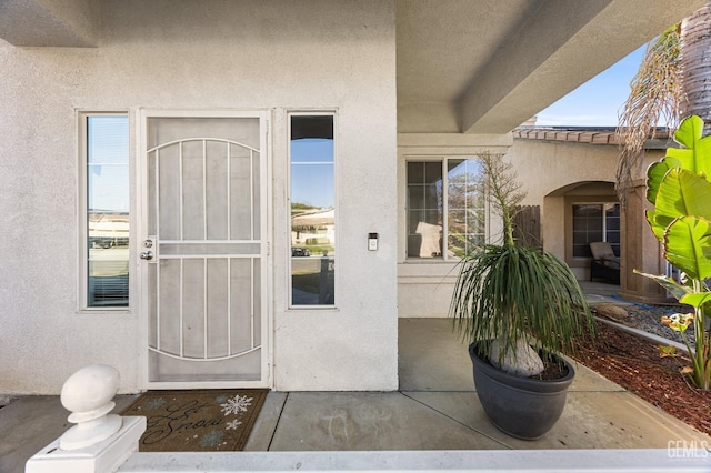 property entrance with a patio, a tiled roof, and stucco siding