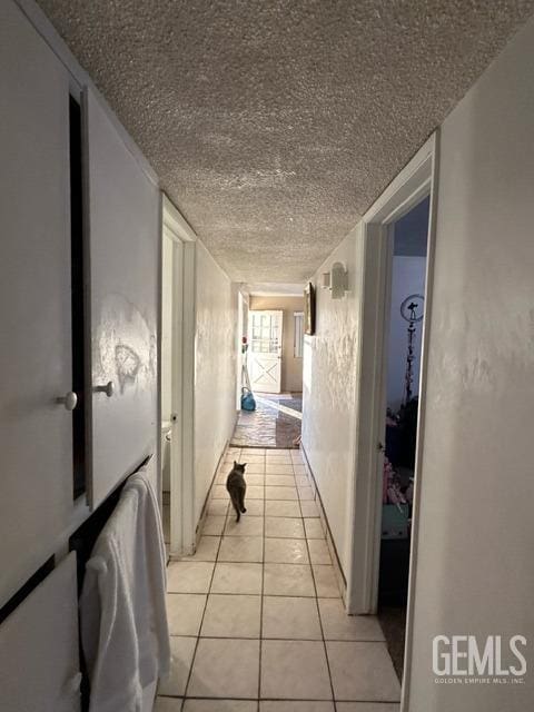 hallway featuring light tile patterned floors and a textured ceiling