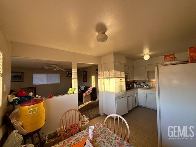 kitchen with white cabinets, white fridge, and ceiling fan