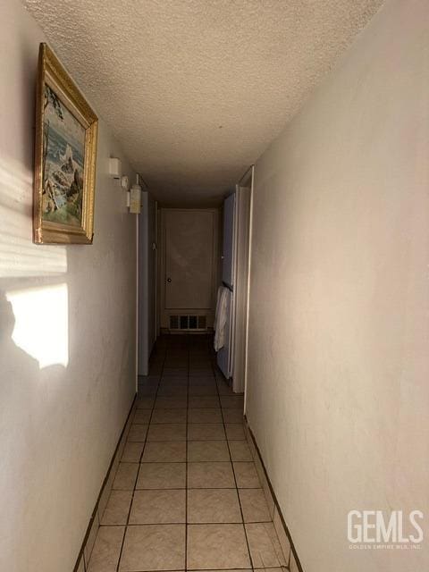 hall featuring light tile patterned flooring and a textured ceiling