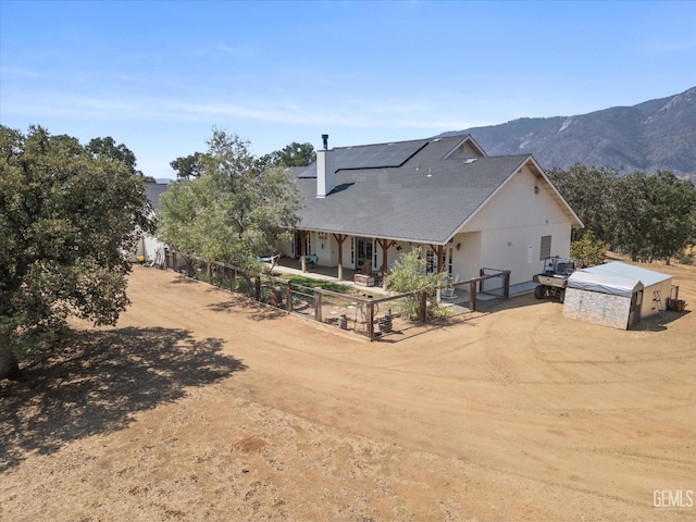 back of property featuring a mountain view and an outdoor structure