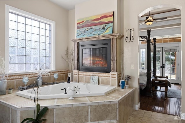 bathroom featuring tile patterned floors, tiled bath, ceiling fan, and french doors