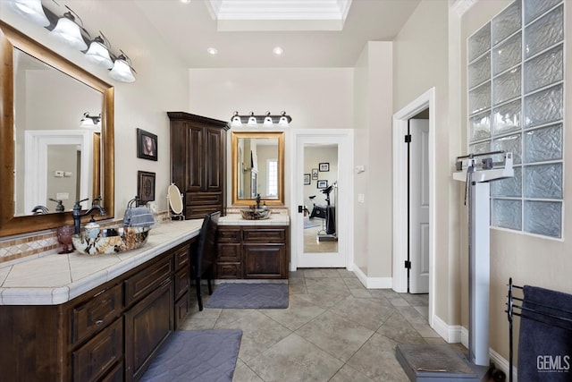 bathroom with a raised ceiling, tile patterned flooring, vanity, and ornamental molding