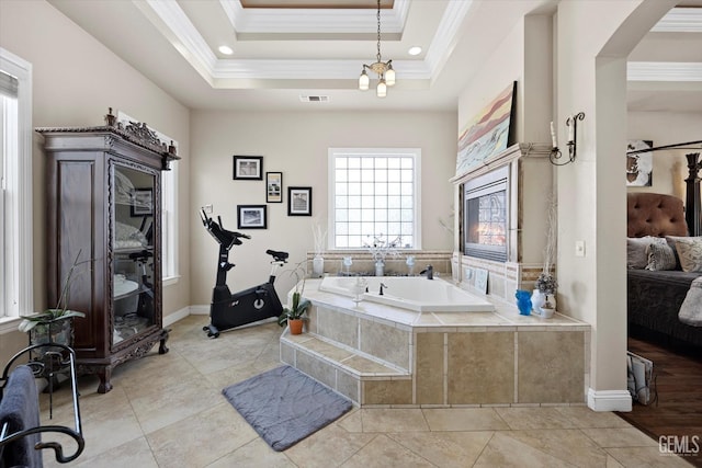 bathroom with tile patterned floors, a tray ceiling, crown molding, a relaxing tiled tub, and a chandelier