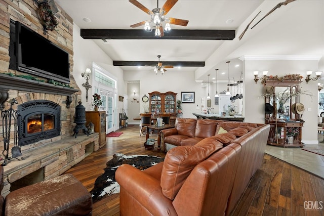 living room with beam ceiling, a stone fireplace, ceiling fan, and dark hardwood / wood-style floors