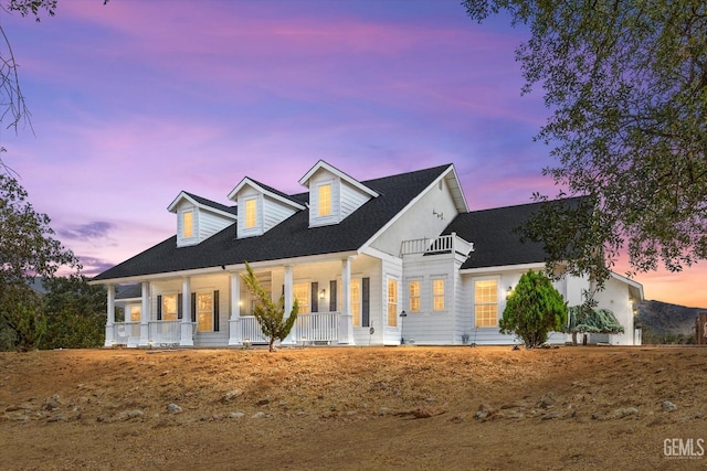 cape cod home with covered porch and a balcony