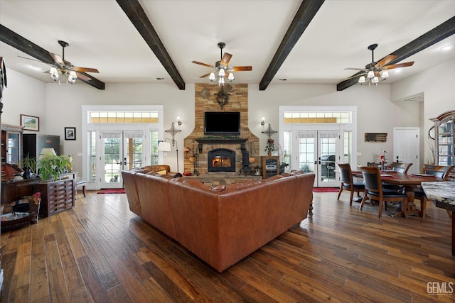 living room with a stone fireplace, ceiling fan, french doors, and dark wood-type flooring