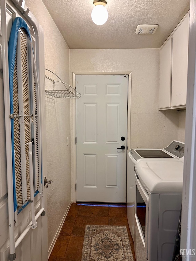 laundry area featuring cabinets, washing machine and clothes dryer, and a textured ceiling