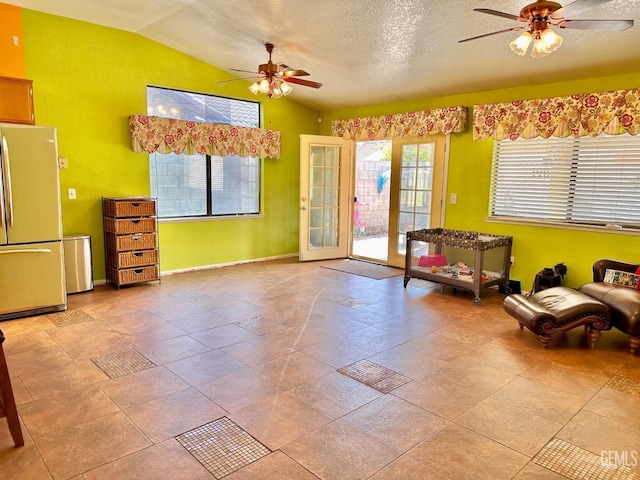 living area featuring lofted ceiling, a textured ceiling, ceiling fan, and french doors