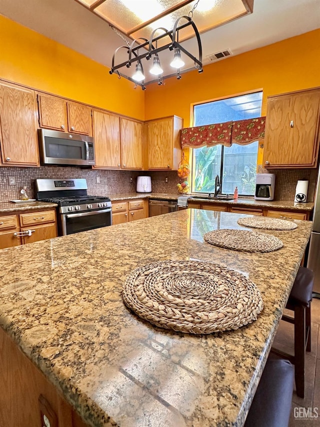 kitchen featuring appliances with stainless steel finishes, tasteful backsplash, sink, a kitchen bar, and light stone counters