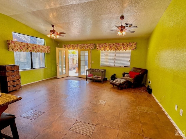 living area with lofted ceiling, light tile patterned floors, a textured ceiling, and ceiling fan