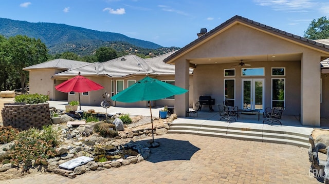 back of property with a patio area, ceiling fan, french doors, and a mountain view