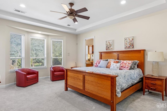 carpeted bedroom featuring ensuite bathroom, a raised ceiling, and ceiling fan