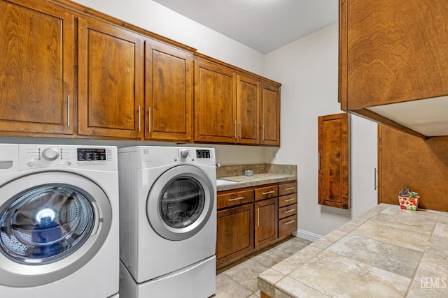 clothes washing area featuring cabinets, separate washer and dryer, and light tile patterned floors