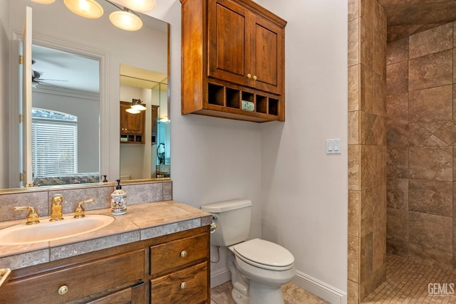 bathroom featuring a tile shower, vanity, toilet, and ceiling fan