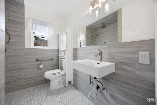 bathroom featuring walk in shower, toilet, sink, tile walls, and tile patterned flooring