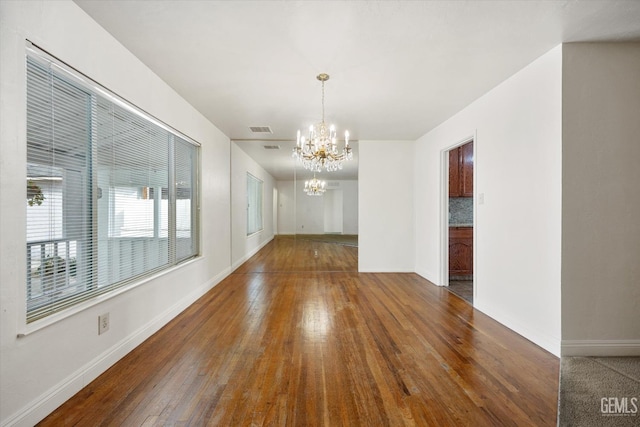 spare room featuring an inviting chandelier and dark hardwood / wood-style flooring