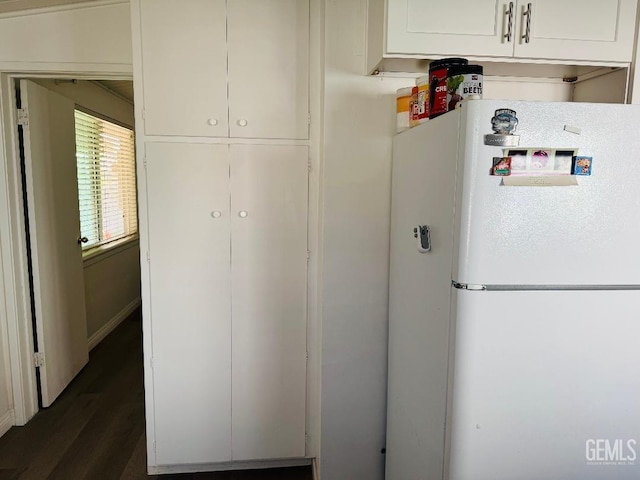 interior space with light countertops, dark wood-type flooring, freestanding refrigerator, and white cabinetry