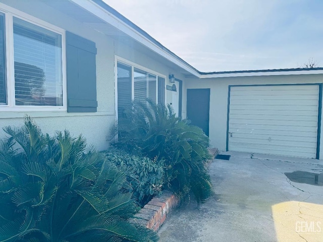 view of home's exterior featuring concrete driveway, an attached garage, and stucco siding