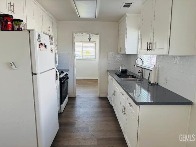 kitchen with a sink, visible vents, white cabinetry, freestanding refrigerator, and gas stove