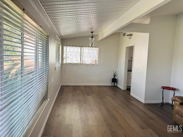 spare room featuring lofted ceiling, baseboards, and wood finished floors