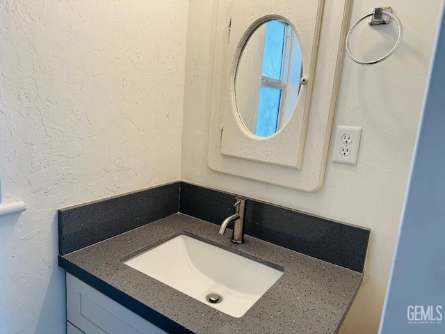 bathroom with a textured wall and vanity