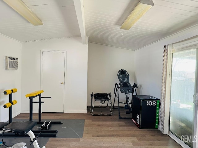 exercise room with lofted ceiling, baseboards, wood finished floors, and a wall mounted air conditioner