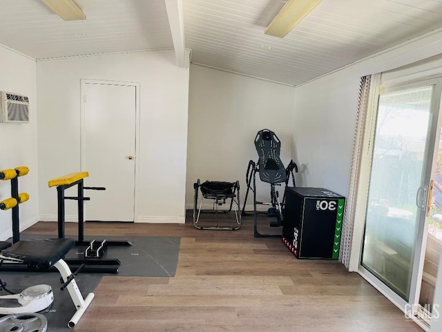 workout area with lofted ceiling, a wall mounted air conditioner, wood finished floors, and baseboards