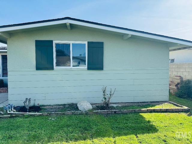 view of side of home featuring a lawn and fence