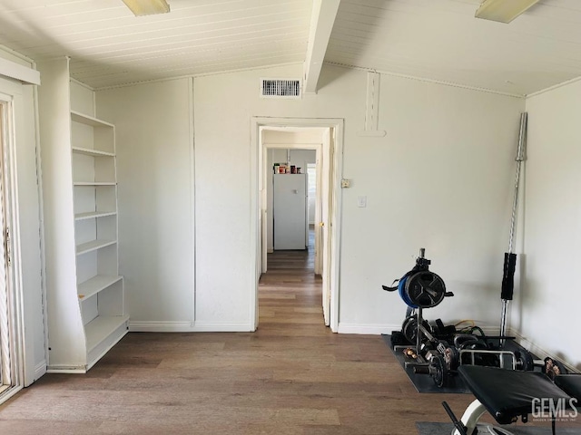 interior space featuring lofted ceiling, visible vents, baseboards, and wood finished floors