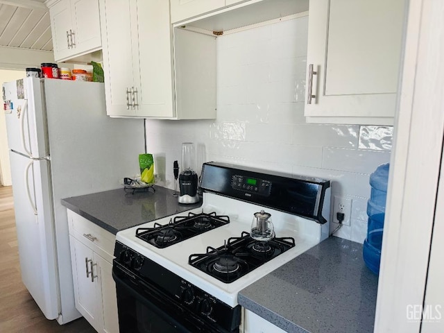 kitchen featuring gas range oven, dark countertops, decorative backsplash, and white cabinets