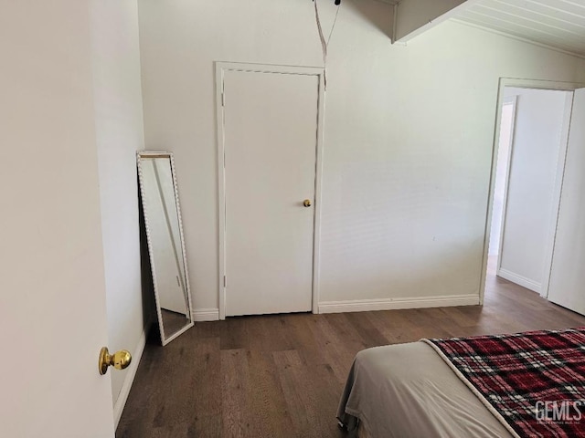 unfurnished bedroom with lofted ceiling, wood finished floors, and baseboards