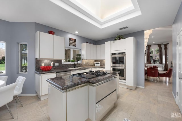 kitchen featuring white cabinets, a kitchen island, stainless steel appliances, and a wealth of natural light