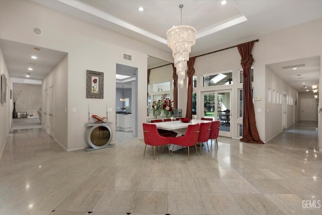 dining space featuring a raised ceiling, a towering ceiling, and an inviting chandelier