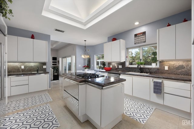 kitchen with a center island, sink, a raised ceiling, white cabinets, and appliances with stainless steel finishes