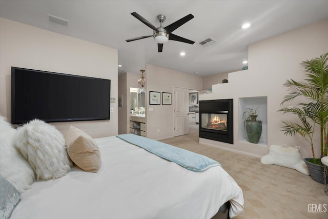 carpeted bedroom featuring ceiling fan, a multi sided fireplace, and ensuite bath