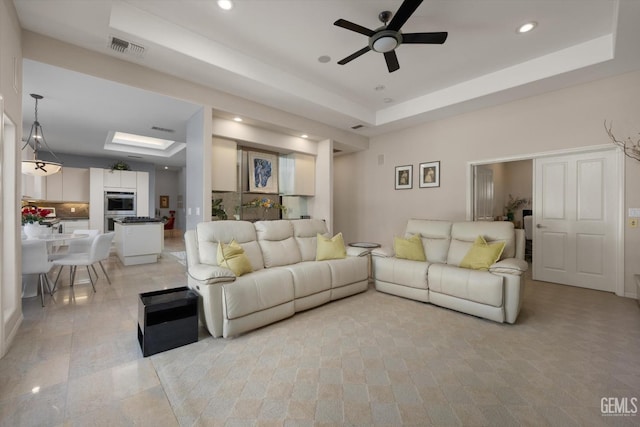 living room with a tray ceiling and ceiling fan