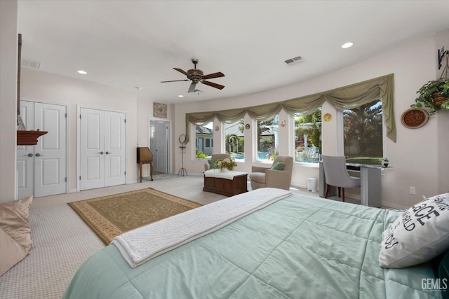 carpeted bedroom featuring ceiling fan and two closets