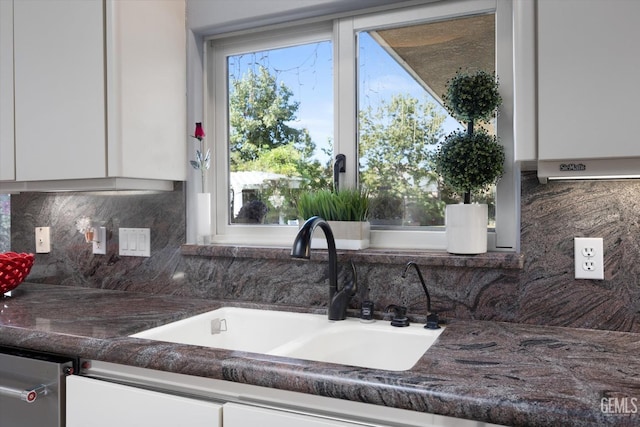 kitchen with backsplash, white cabinetry, and sink