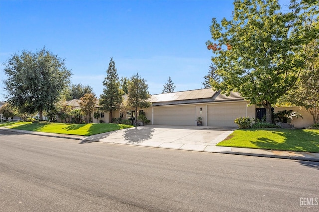 view of front of home featuring a front lawn, a garage, and solar panels