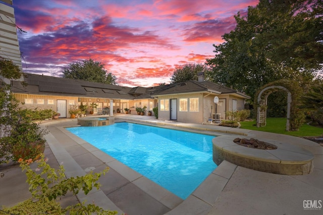 pool at dusk with an in ground hot tub, a fire pit, and a patio area