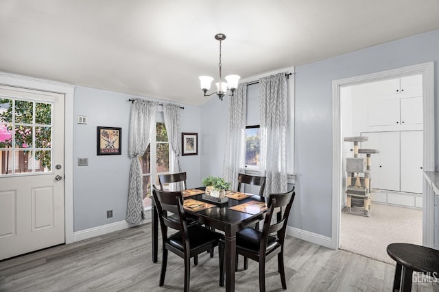 dining room featuring light wood-type flooring, baseboards, visible vents, and a chandelier