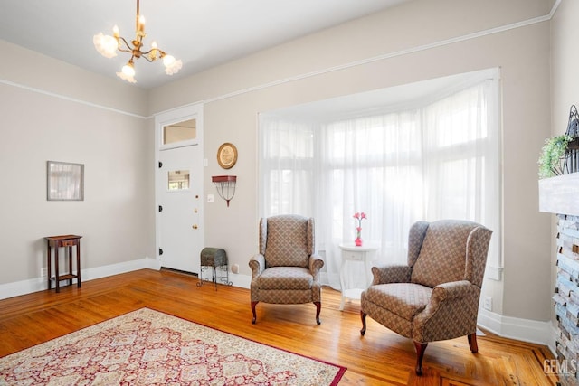 living area with a notable chandelier, baseboards, and wood finished floors