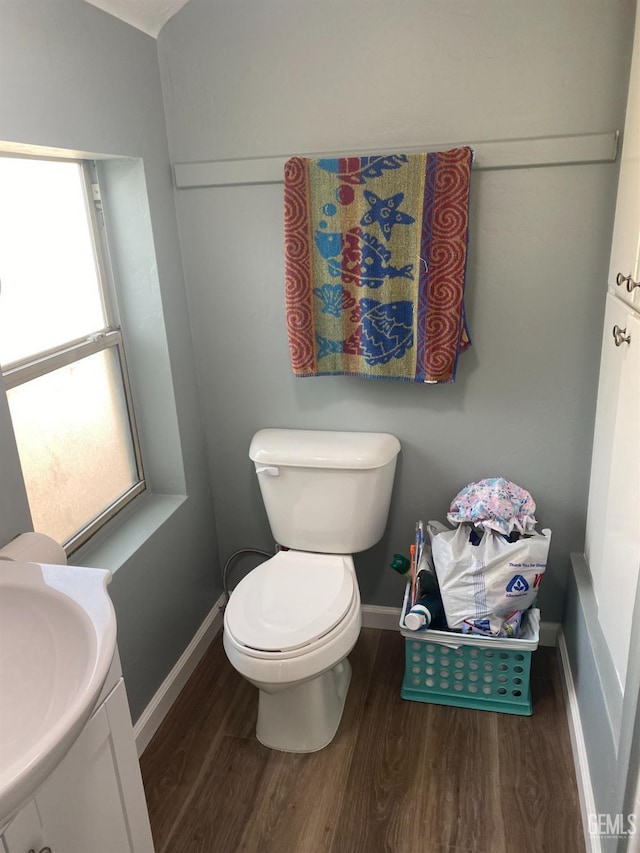 half bathroom featuring baseboards, vanity, toilet, and wood finished floors