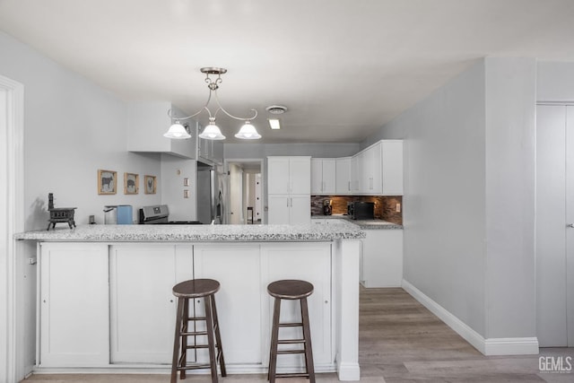 kitchen featuring stainless steel appliances, white cabinets, a peninsula, and a breakfast bar area