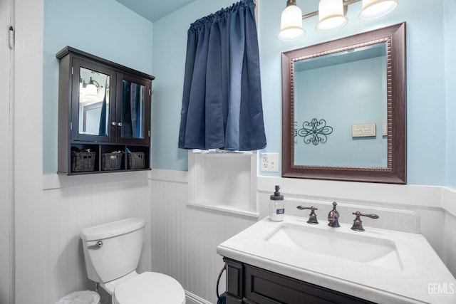 bathroom featuring a wainscoted wall, vanity, and toilet