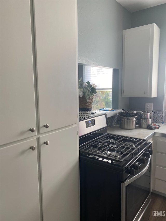 kitchen with light countertops, stainless steel gas range oven, and white cabinetry