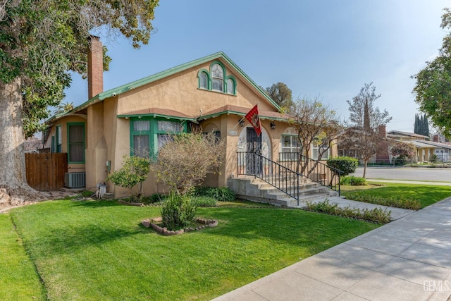 view of front facade with cooling unit, a chimney, a front yard, and stucco siding