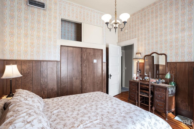 bedroom featuring dark wood-type flooring, wainscoting, visible vents, and wallpapered walls